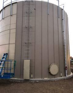 Beige water storage tank with vertical insulation being installed on outside