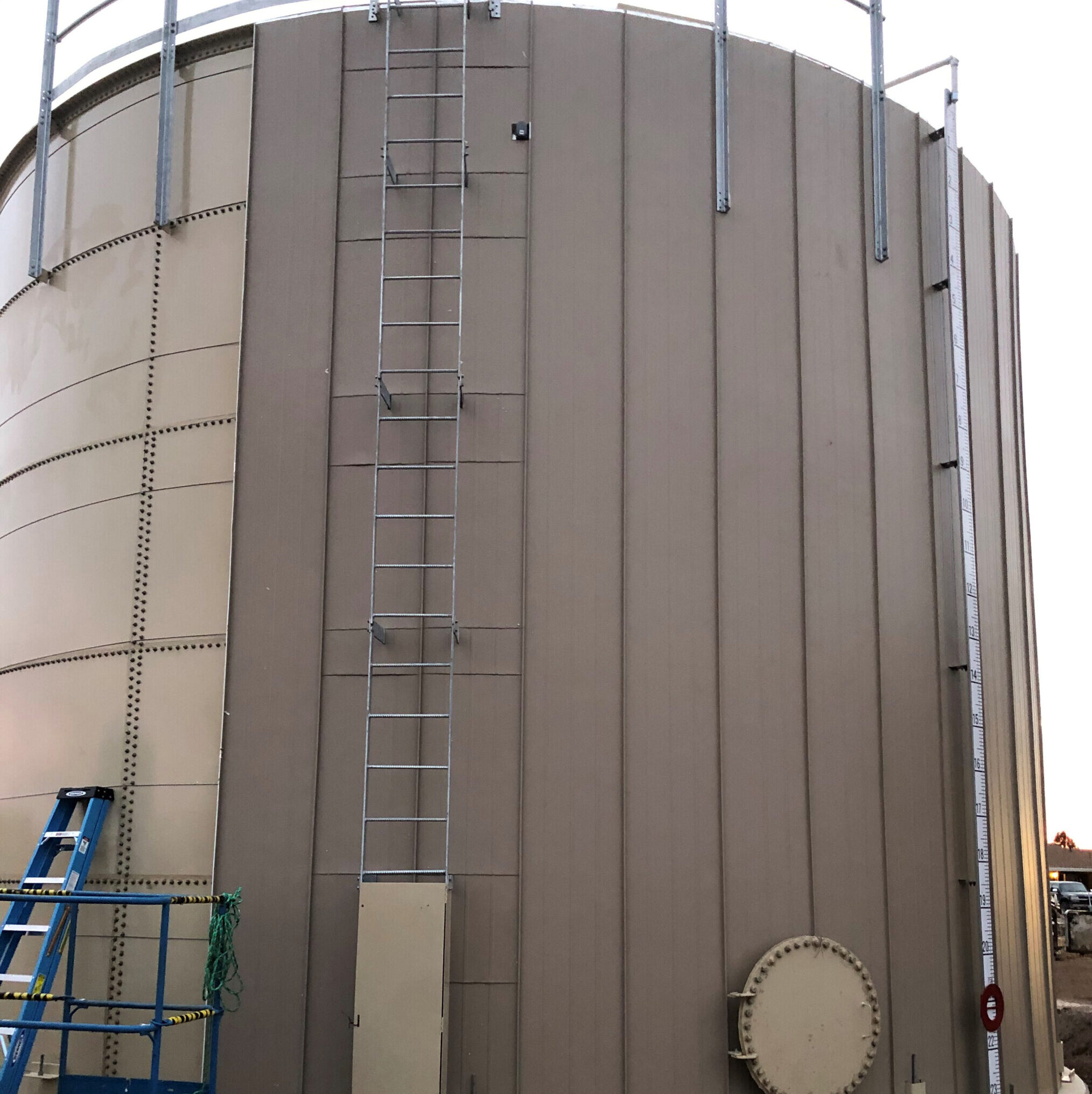 Beige water storage tank with vertical insulation being installed on outside