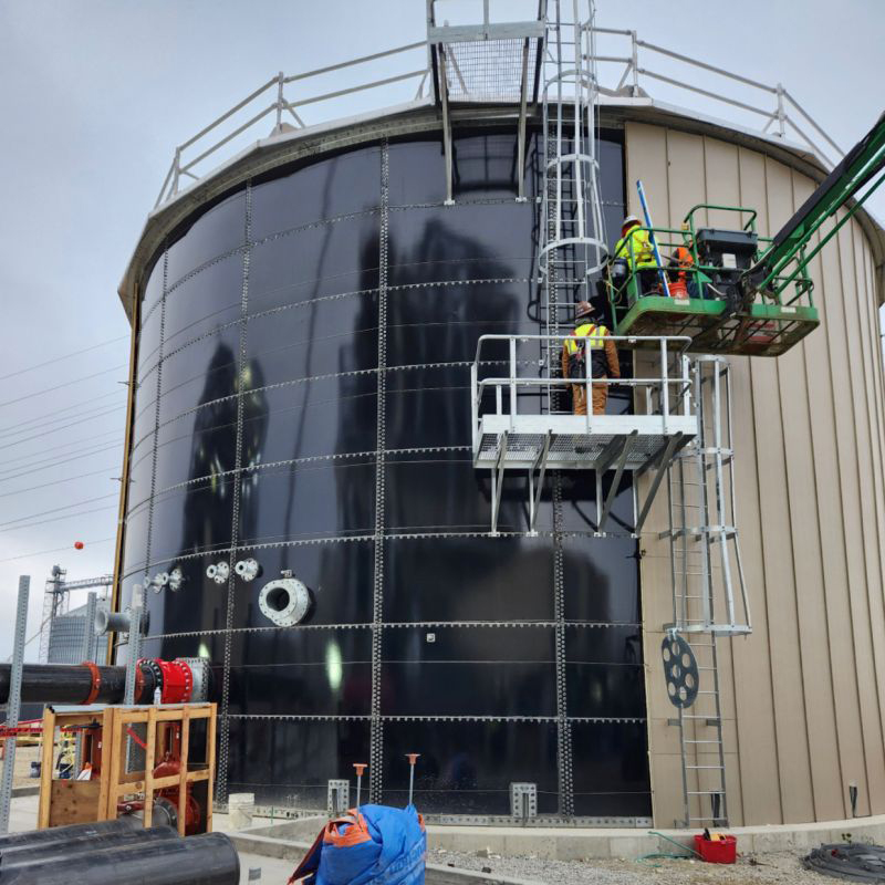 Workers installing Blue bolted water tank with tank insulation.