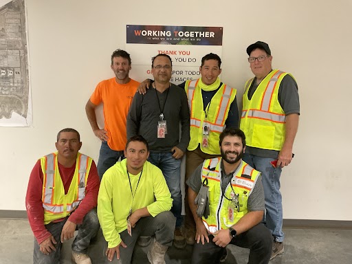 Team of construction workers in yellow vests standing for a photograph