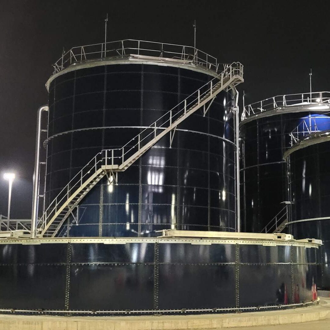 Nighttime view of four , blue, large glass lined water storage tanks in Tennessee